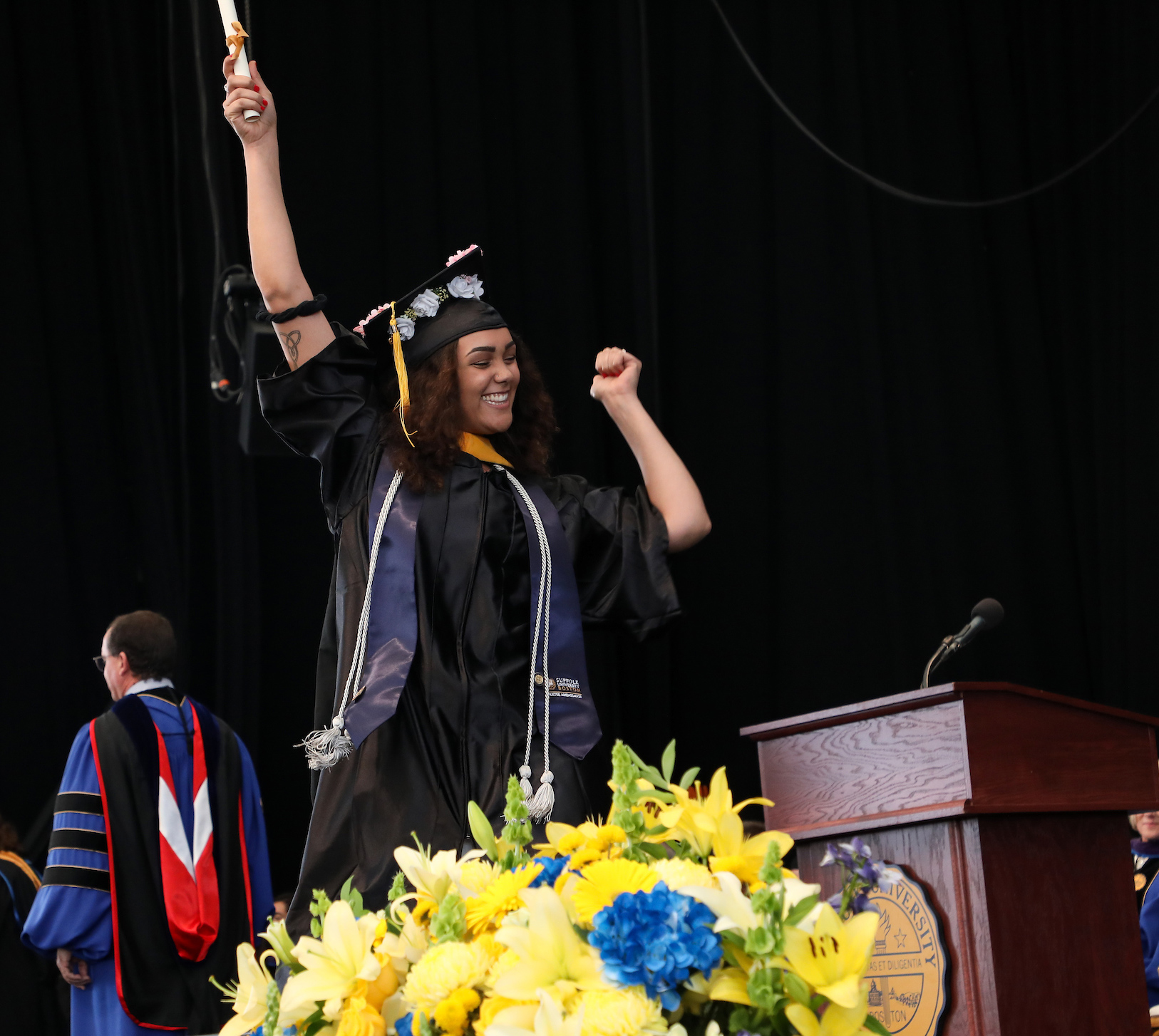 Brenna lifts her scroll high above her head as she crosses the stage at Commencement.