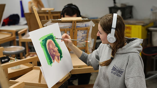 Student in painting class working at an easel