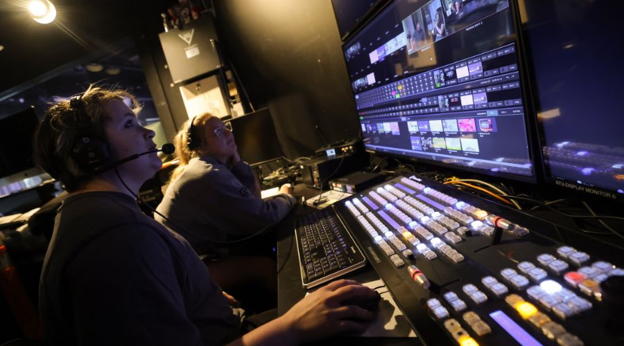 Two people sitting in front of large computer screen