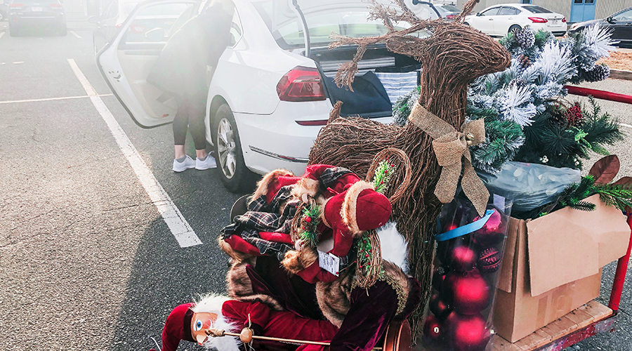 Pile of decorations including grapevine reindeer, elf figures and greens, piled outside a car