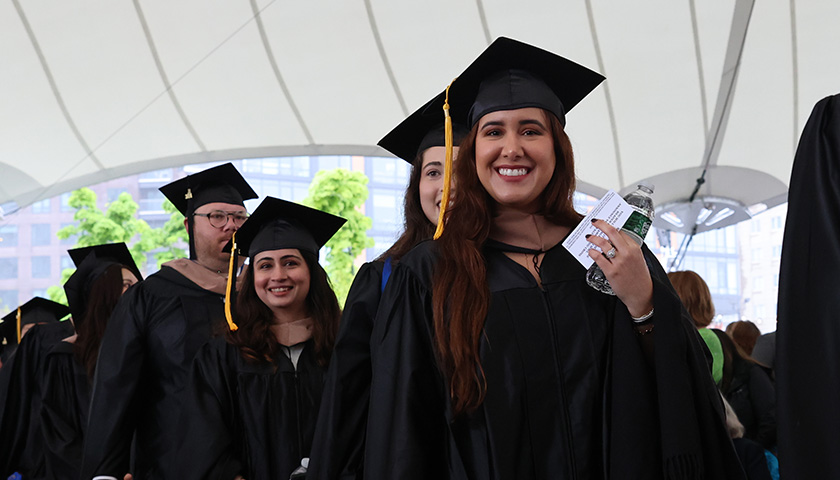 Students smile as they process into Leader Bank Pavilion during SBS Commencement 2024
