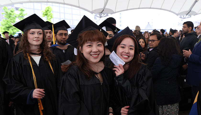 Students smile as they wait to walk across the Commencement stage
