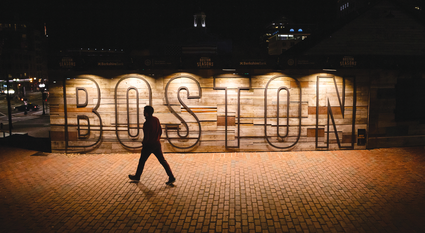 Marquis lights that read BOSTON with a silhouetted person walking in front