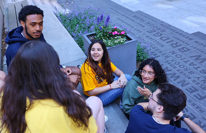 Students sit casually together in Roemer plaza in front of the Samia Academic Center on campus at Suffolk University.