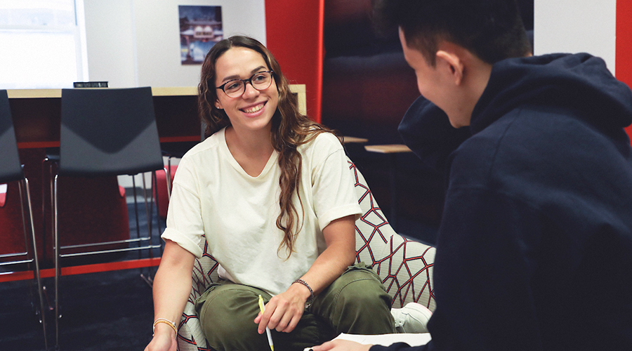A Suffolk transfer student hangs out in a lounge space on campus with a friend.